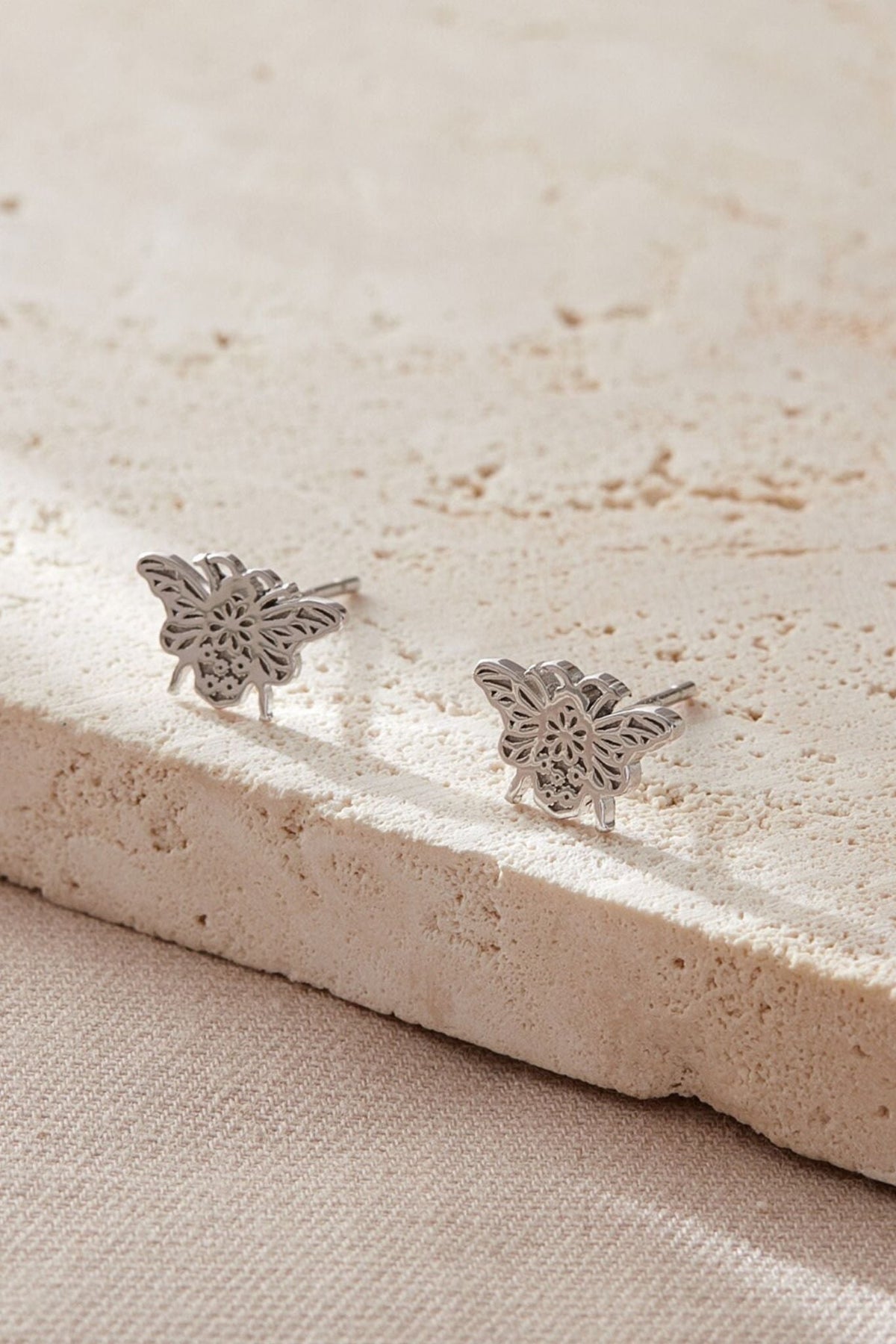 close up of the silver daisy floral pattern on the bee stud earrings