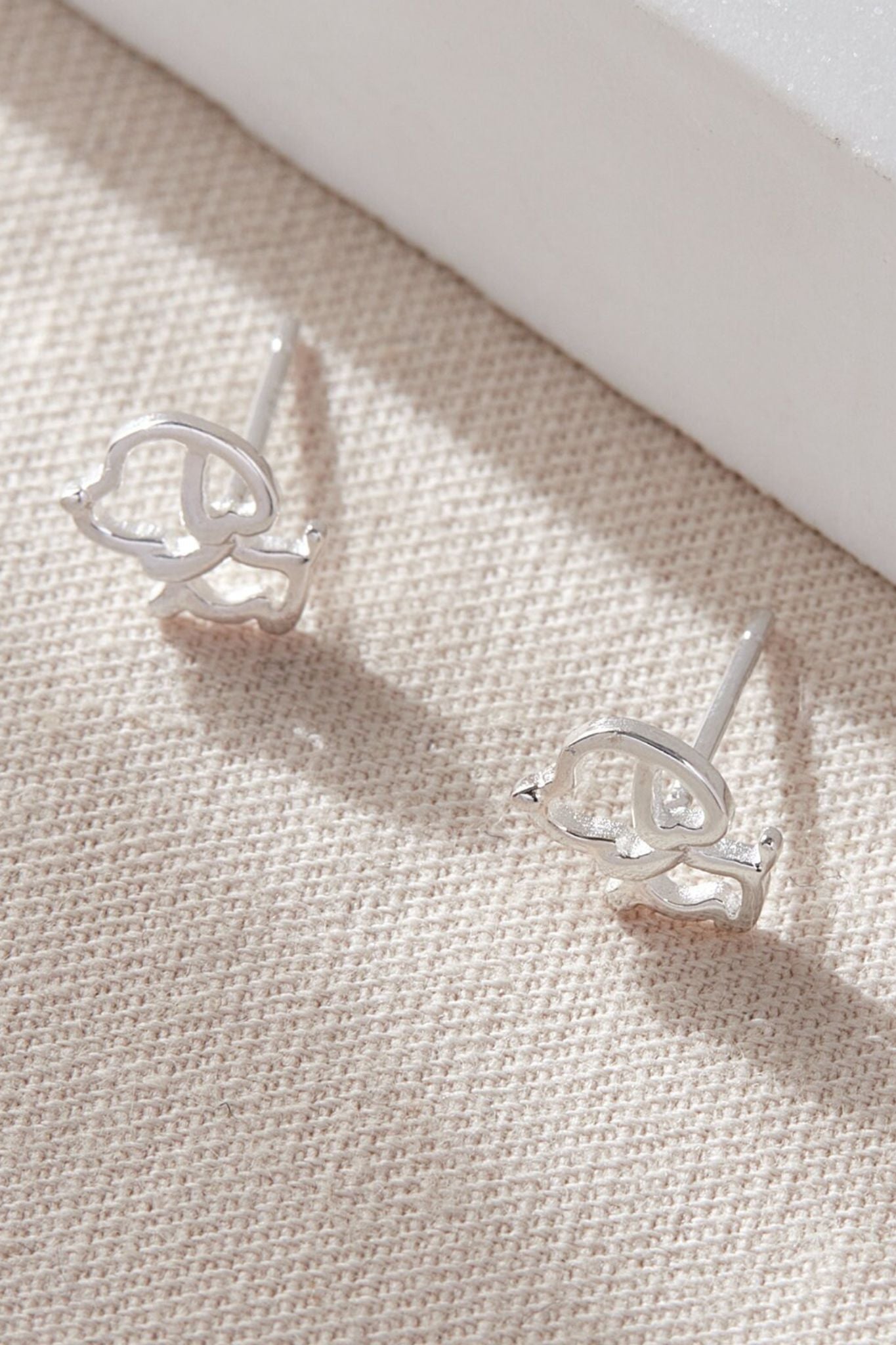 close up of the outline silver dog stud earrings, showing the cartoon like design