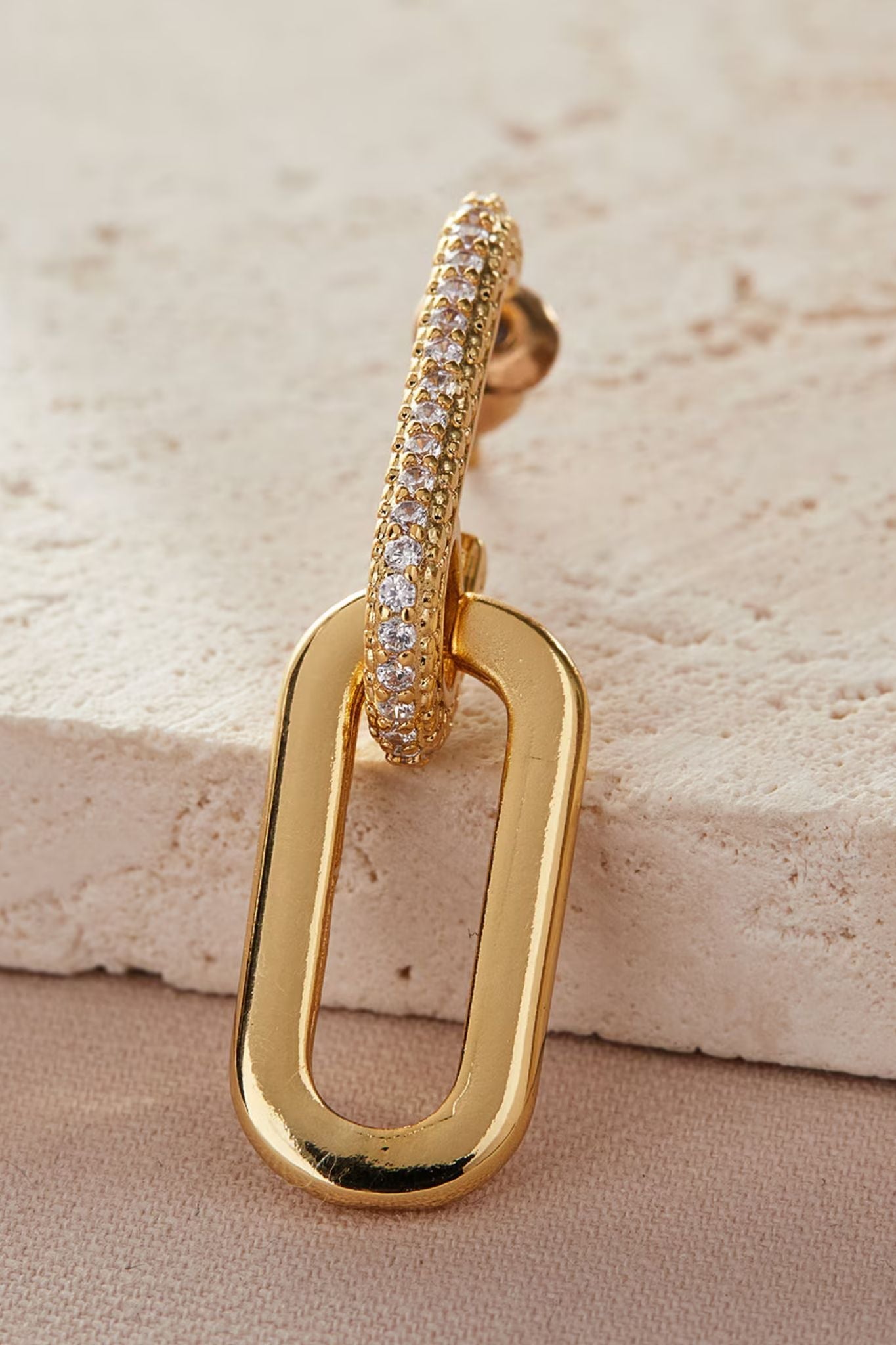 close up of the gold earrings showing a cz encrusted link attached to a plain gold coloured link