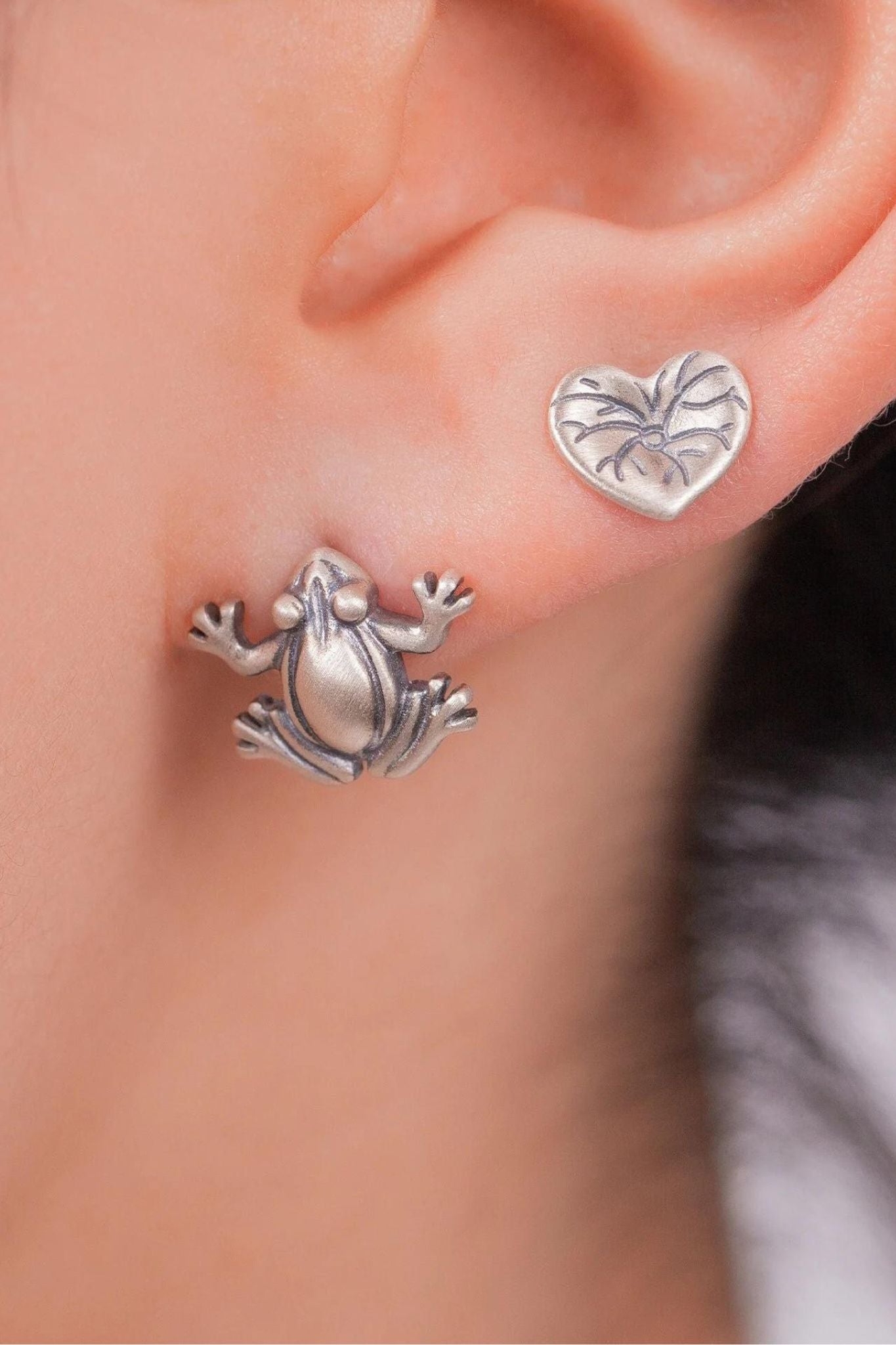 model wearing both frog and lily pad earrings in the earlobe showing the size of the earrings and that they can be worn stacked as shown