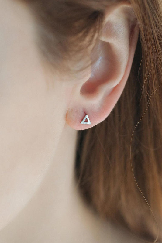model wearing a silver triangle outline stud earring on the earlobe, showing the dainty size of the earrings