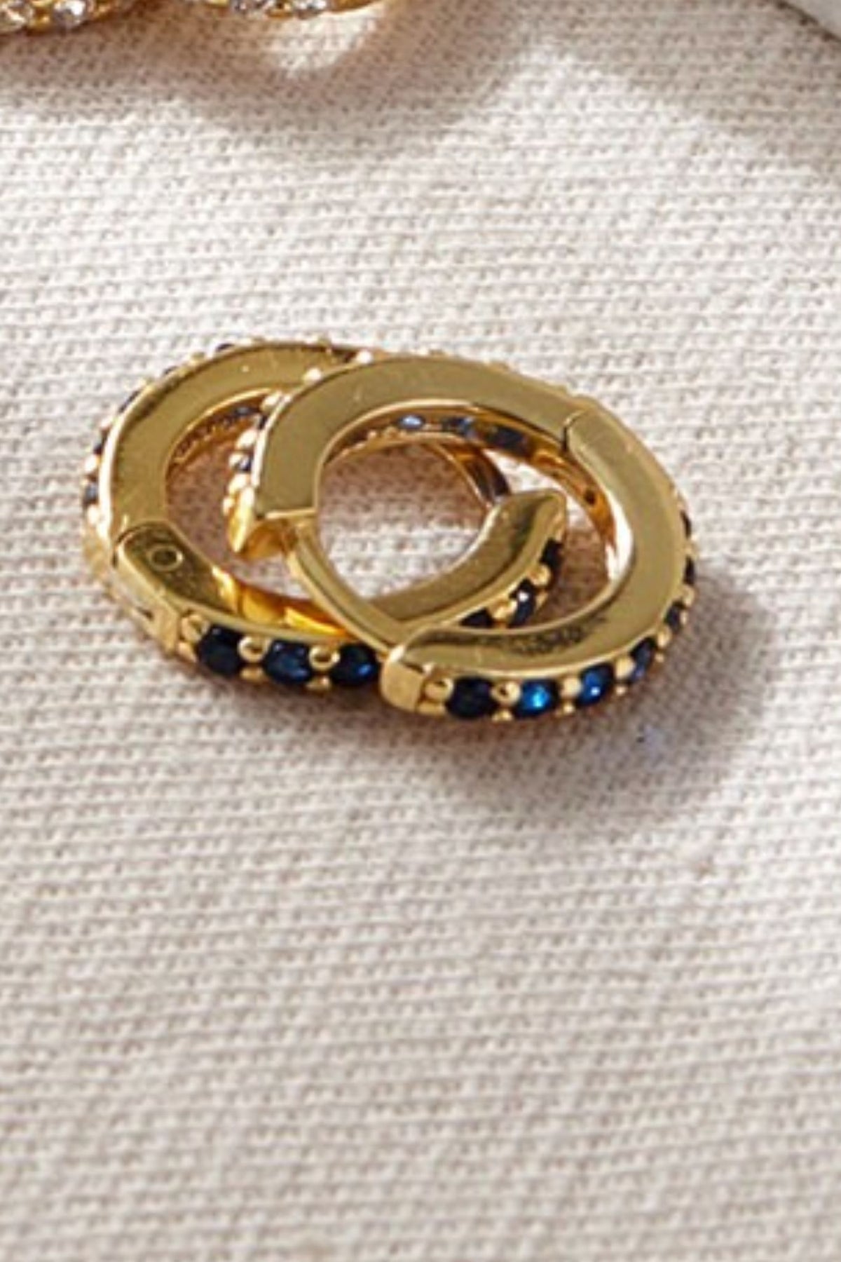 sterling-silver-cz-huggie-hoops-in-gold-blue-closeup