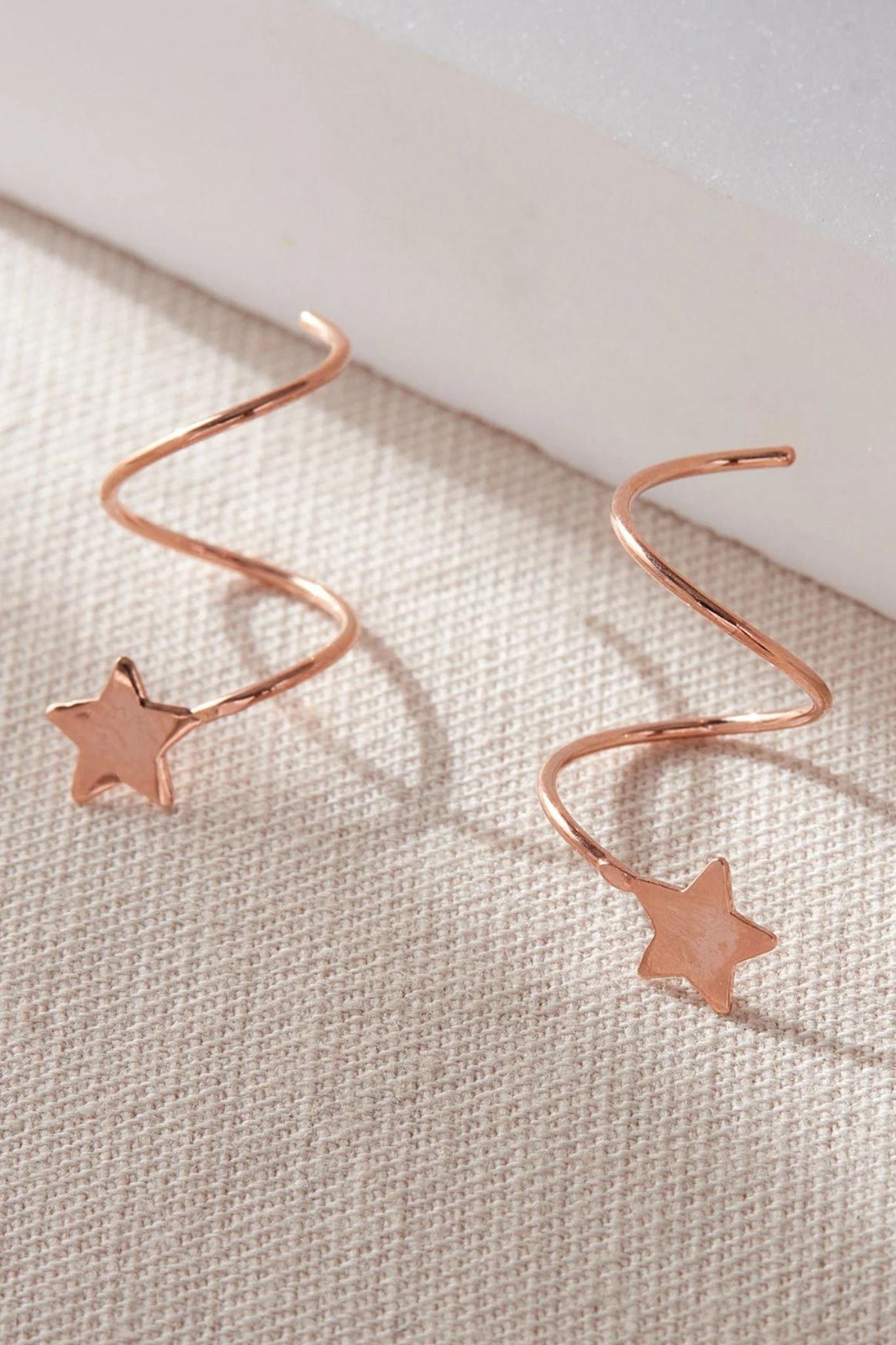 close up of the rose gold coloured s925 sterling silver star climber earrings
